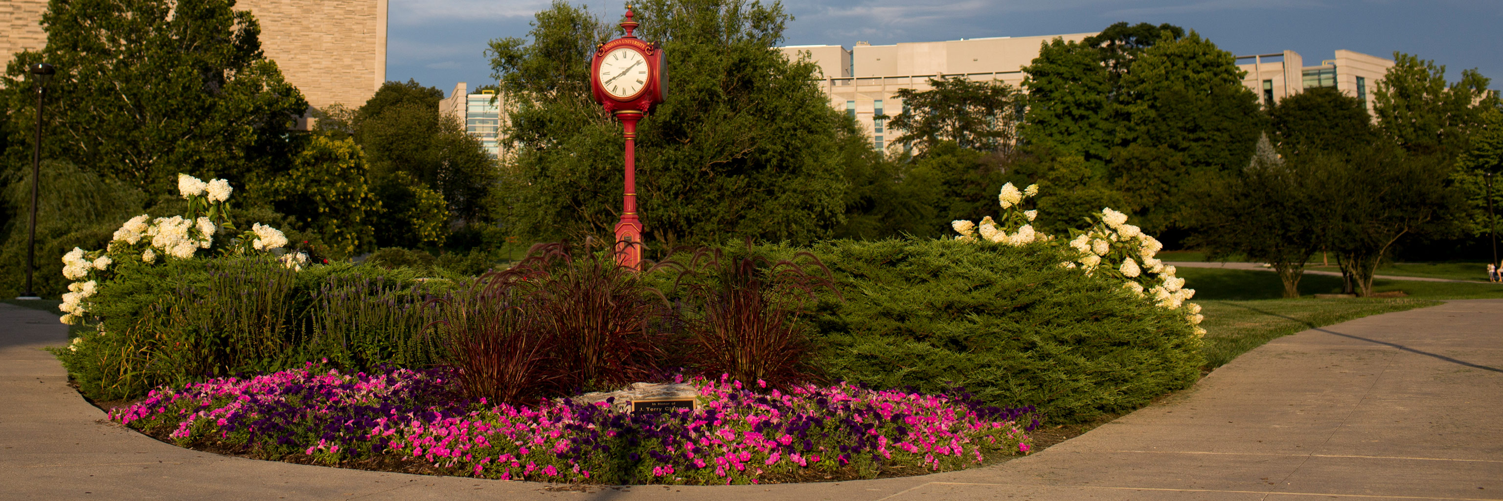 Flowers and trees next to red ornamental clock